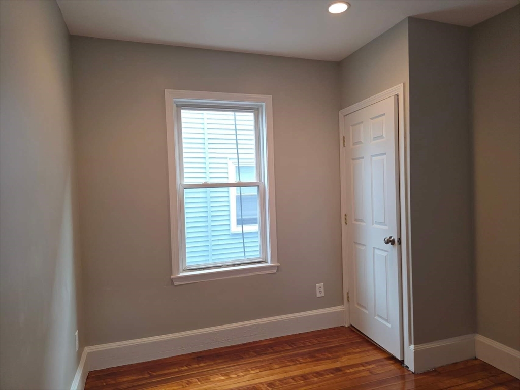 574 Washington Street, Unit 2 Boston, MA 02135 - Photo 8 of 11 an empty room with wooden floor and windows
