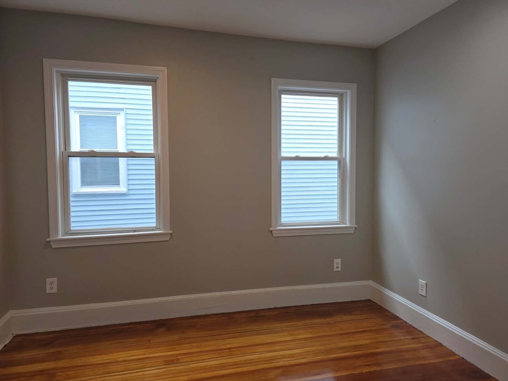 574 Washington Street, Unit 2 Boston, MA 02135 - Photo 9 of 11 a view of an empty room with wooden floor and a window