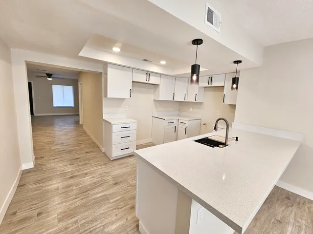 a kitchen with white cabinets a sink dishwasher and a stove with wooden floor