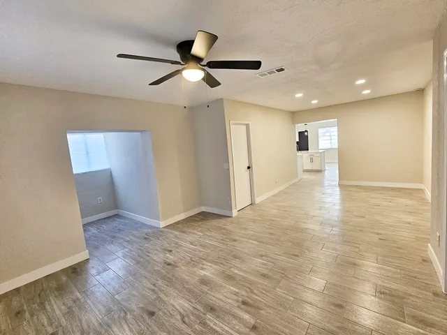 an empty room with windows and fan