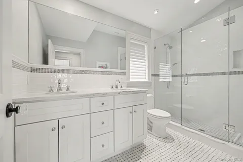 a bathroom with a double vanity sink toilet and shower