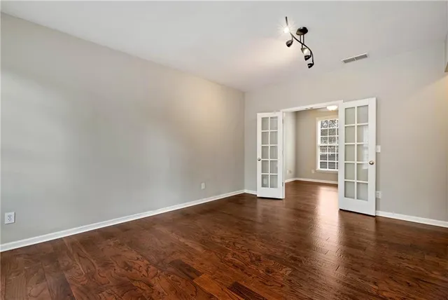 an empty room with wooden floor and windows