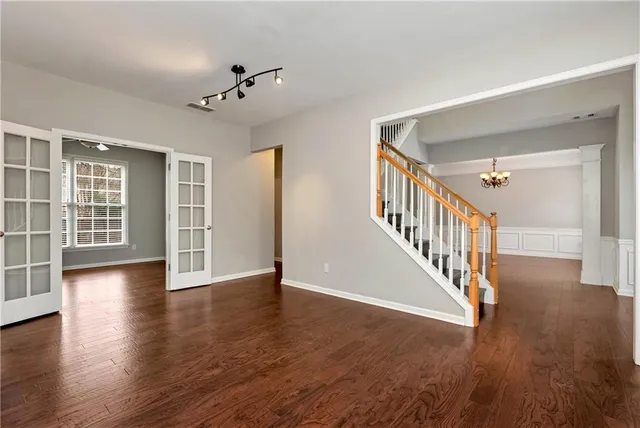 an empty room with wooden floor and windows