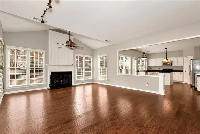 a view of an empty room with wooden floor fireplace and a window
