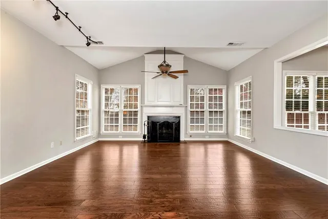 a view of an empty room with window and wooden floor