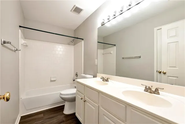 an empty room with wooden floor ceiling fan and windows