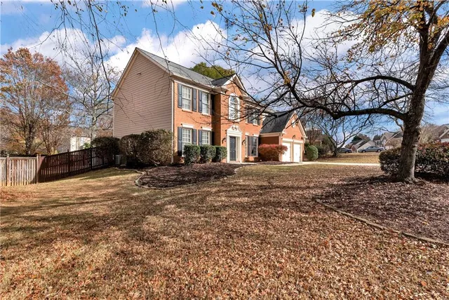 a view of a brick house with many windows and a yard