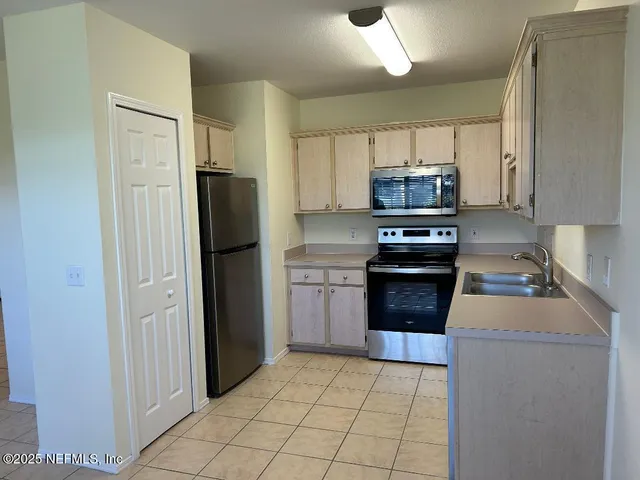 a kitchen with granite countertop a refrigerator and a stove top oven