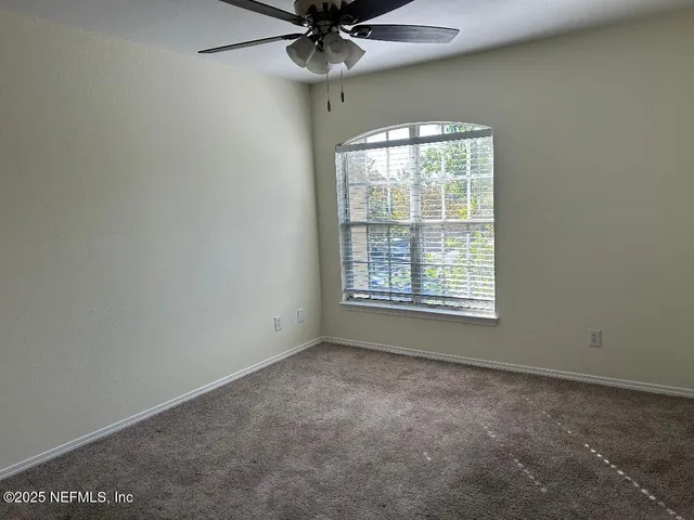 an empty room with a ceiling fan and window