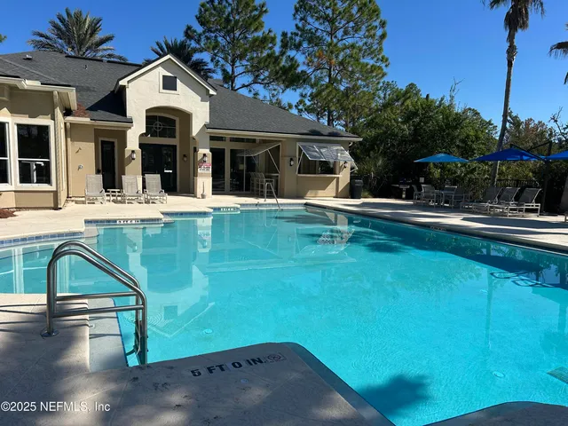 a view of swimming pool with lawn chairs and plants