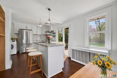a kitchen with stainless steel appliances a refrigerator a sink dishwasher a stove and white cabinets with wooden floor