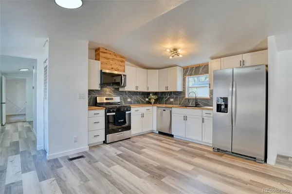 a kitchen with granite countertop a refrigerator and a stove top oven