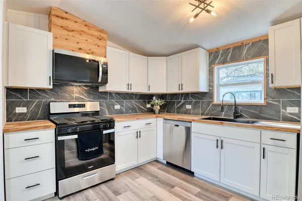 a kitchen with stainless steel appliances granite countertop a sink a stove and a microwave