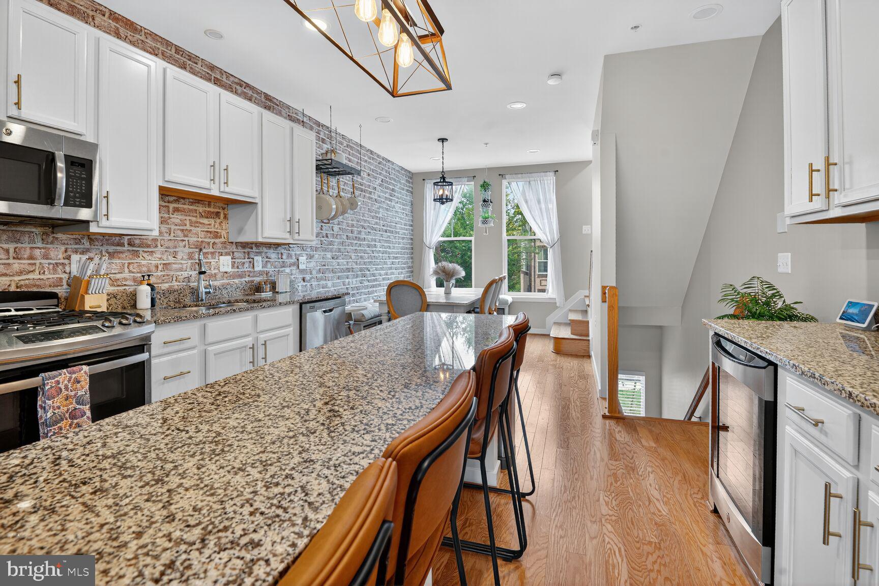 1449 Trafalgar Lane Frederick, MD 21701 - Photo 9 of 28 a kitchen with stainless steel appliances granite countertop a stove top oven a sink dishwasher a dining table and chairs with wooden floor