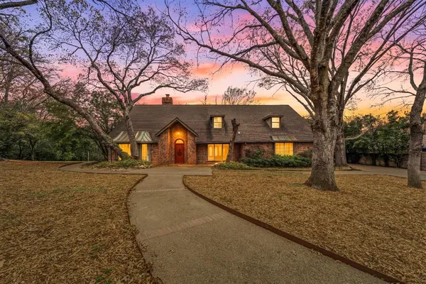 a front view of a house with a yard and large tree