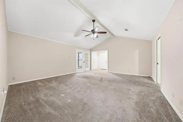 a view of a room with a ceiling fan and carpet