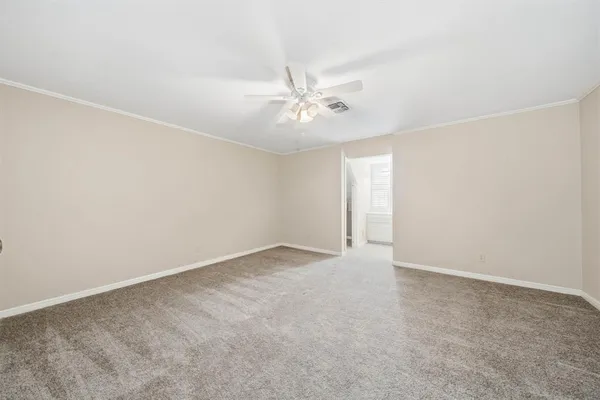 an empty room with a chandelier fan and windows