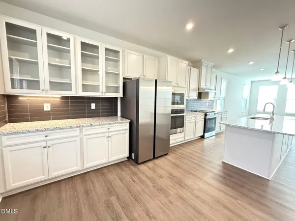 a kitchen with stainless steel appliances granite countertop a refrigerator a stove and a granite countertops with wooden floor