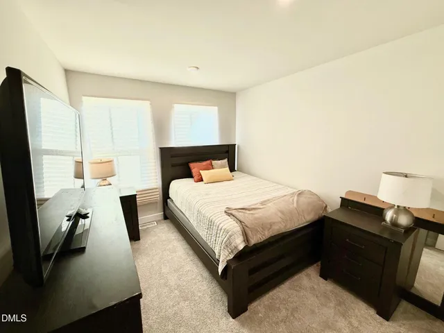 a bedroom with a bed and a flat tv screen on dresser
