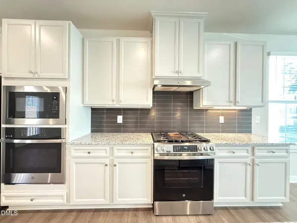 a kitchen with stainless steel appliances a stove and white cabinets