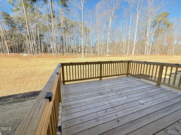 a view of a deck with wooden floor and fence next to a yard