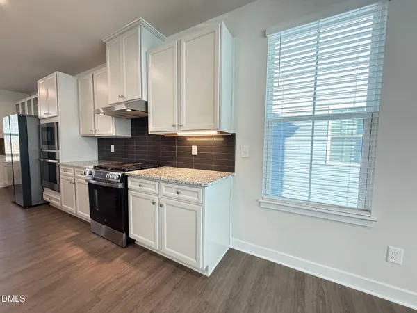a kitchen with granite countertop white cabinets and wooden floor