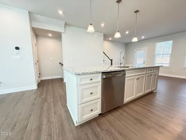 a kitchen with stainless steel appliances granite countertop a sink a stove and wooden floors