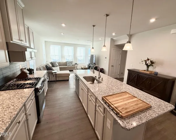 a large kitchen with kitchen island a stove a sink a refrigerator a stove a dining table and chairs with wooden floor