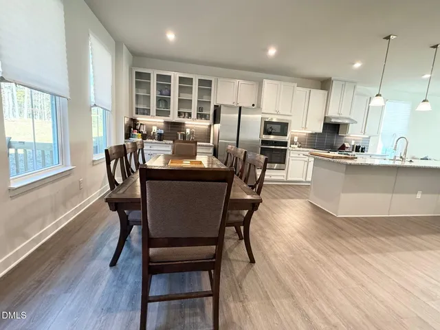 a dining room with stainless steel appliances kitchen island granite countertop a table chairs and a refrigerator