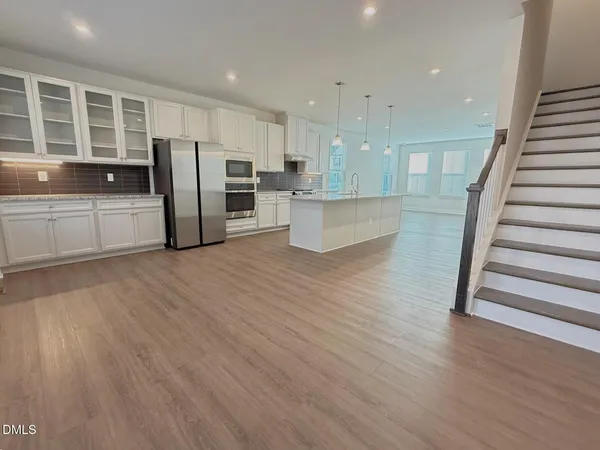 a view of kitchen with stainless steel appliances refrigerator oven and wooden floor