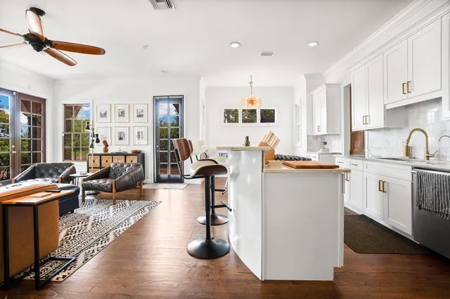 a living room with furniture a rug kitchen view and a large window
