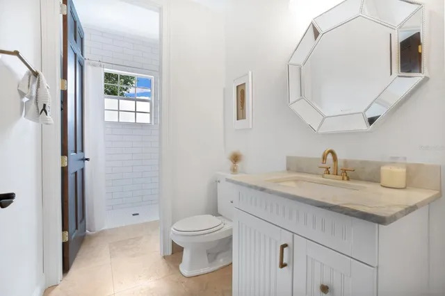 a bathroom with a granite countertop sink a toilet and a mirror