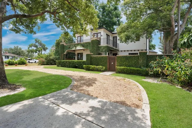a front view of a house with a yard and potted plants
