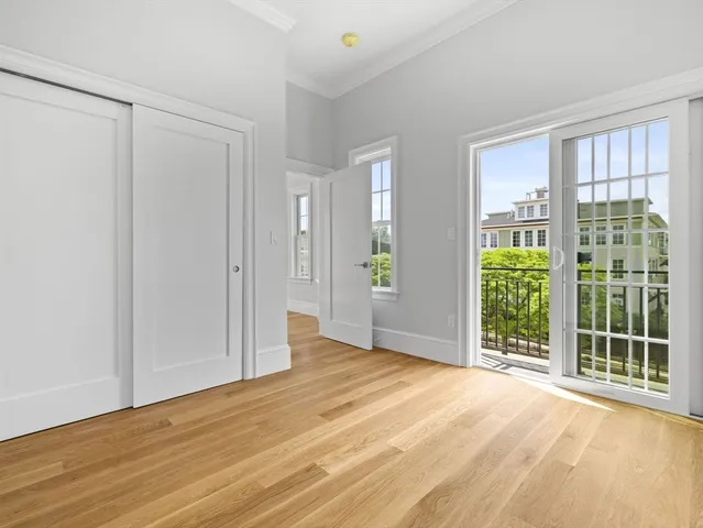 a view of an empty room with wooden floor and windows