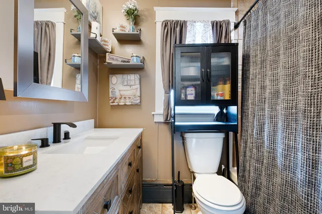 a view of a white house next to a yard with wooden fence