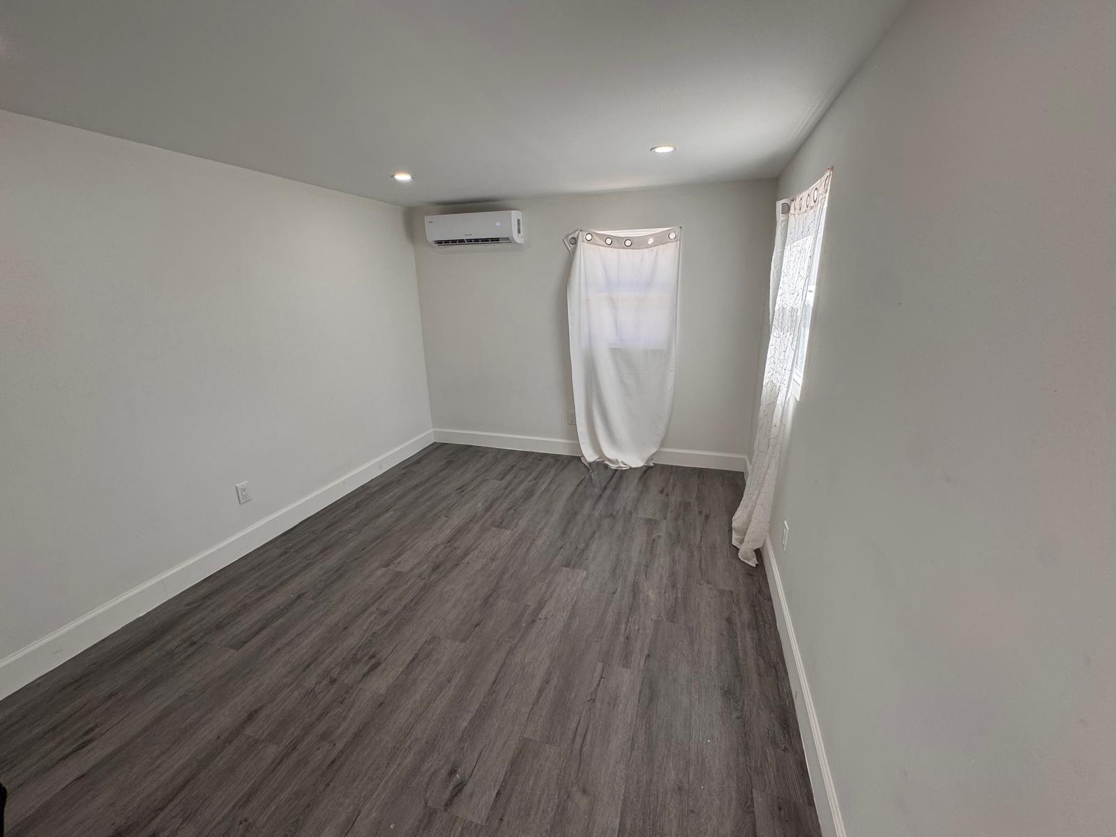 357 Hunting Club Avenue Clewiston, FL 33440 - Photo 14 of 37 wooden floor in an empty room with a window