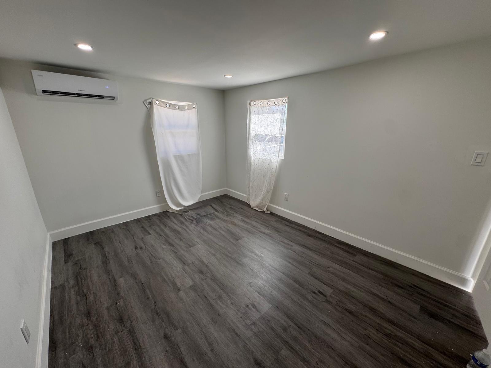 357 Hunting Club Avenue Clewiston, FL 33440 - Photo 15 of 37 an empty room with wooden floor and windows