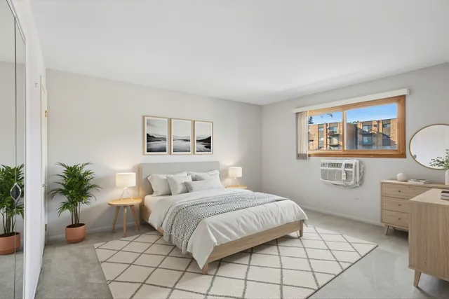 a bedroom with a large bed a potted plant and a window