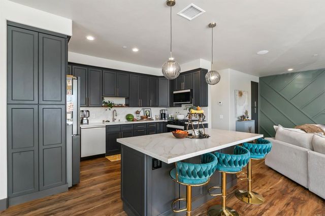 a kitchen with a dining table cabinets stainless steel appliances and wooden floor