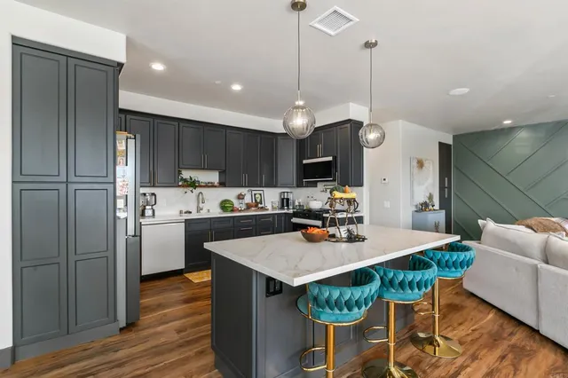 a kitchen with a dining table cabinets stainless steel appliances and wooden floor