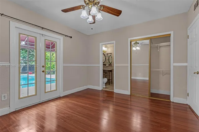 an empty room with wooden floor closet and windows