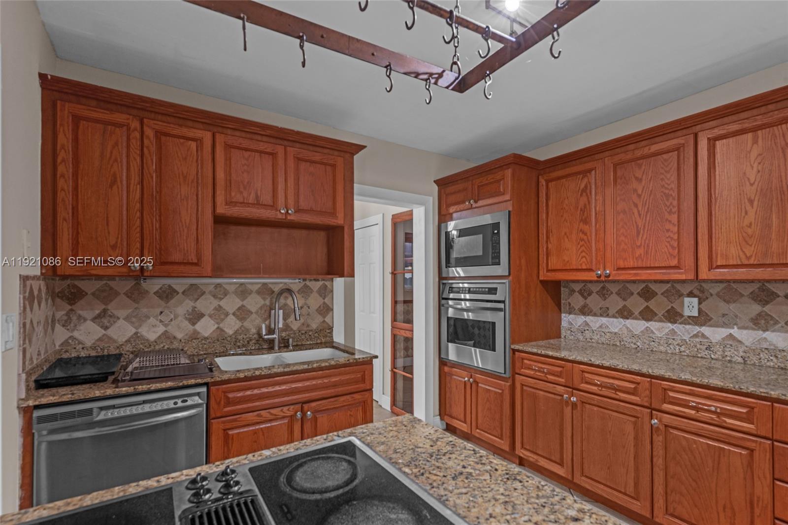 9400 Southwest 193rd Drive, Unit 9400 Cutler Bay, FL 33157 - Photo 26 of 42 a kitchen with granite countertop wooden cabinets and stainless steel appliances