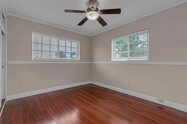 a view of empty room with wooden floor and fan