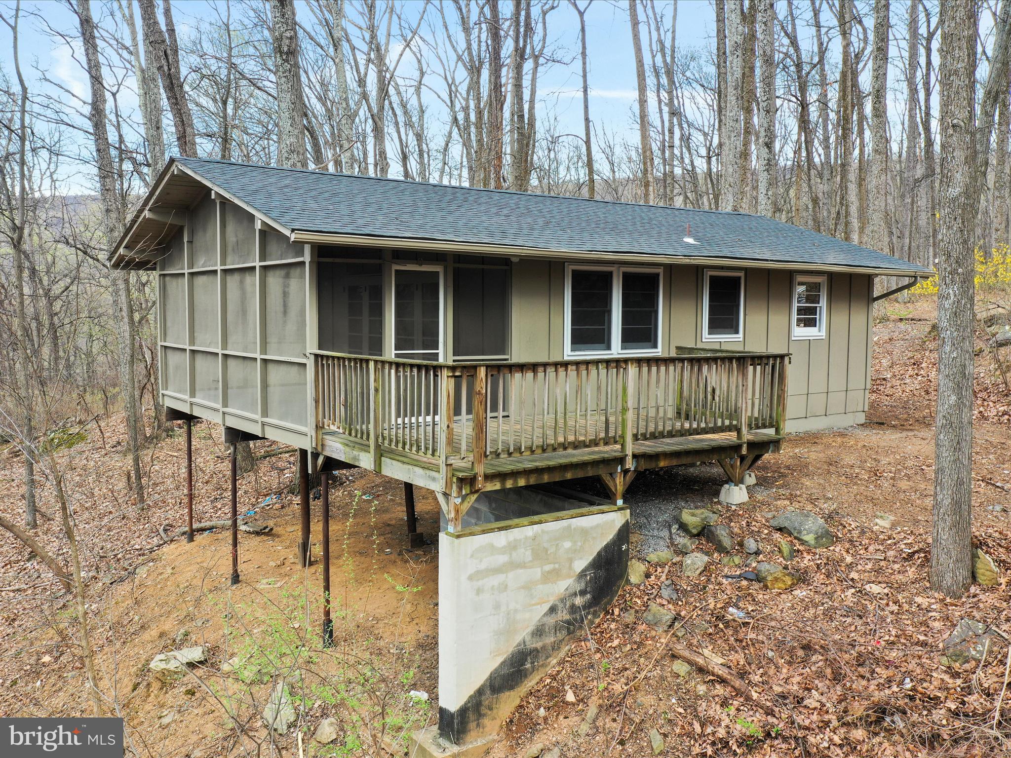 a view of small house with wooden deck front of house