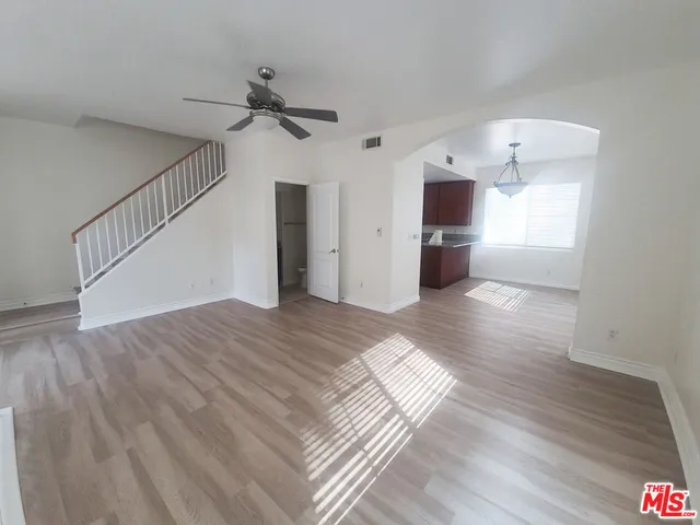 a view of a room with wooden floor and a ceiling fan