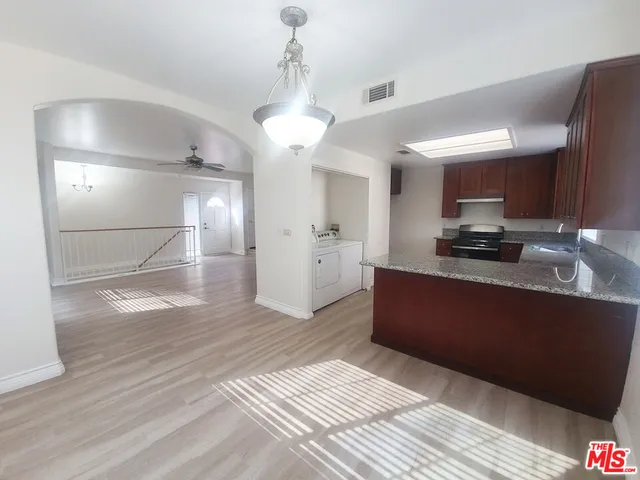 a large kitchen with stainless steel appliances granite countertop a refrigerator a sink dishwasher a stove and white countertops with wooden floor