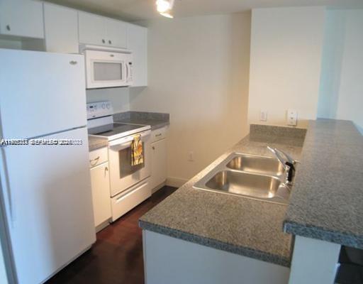 2740 Southwest 28th Terrace, Unit 503 Miami, FL 33133 - Photo 10 of 19 a kitchen with stainless steel appliances granite countertop a sink stove and white cabinets