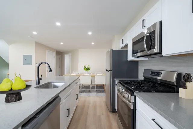 a kitchen with stainless steel appliances granite countertop a sink a stove top oven a counter space and cabinets