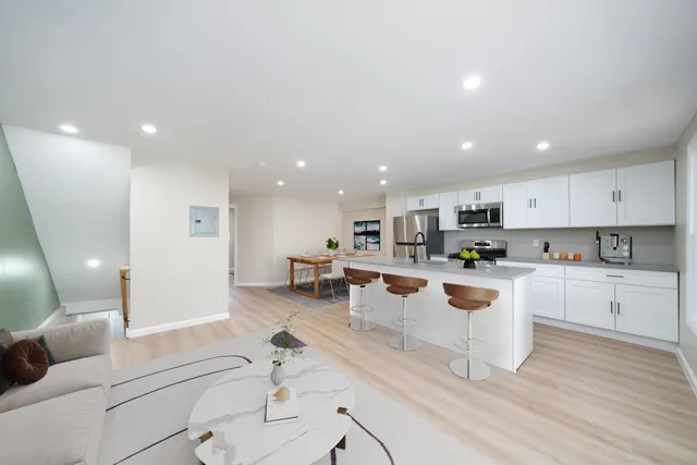 a large white kitchen with lots of counter space a sink appliances and cabinets