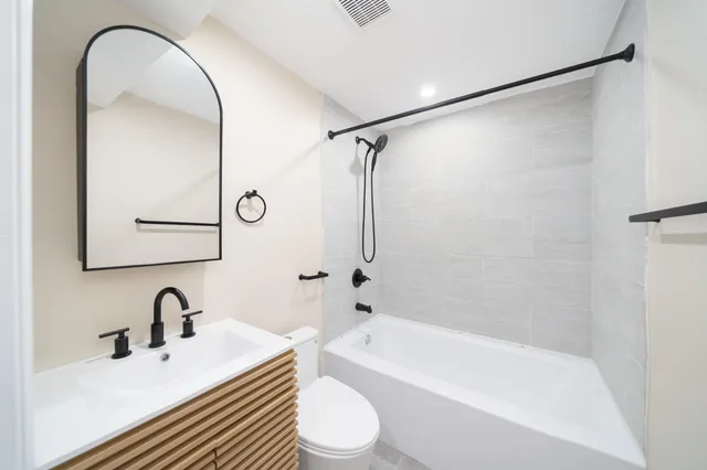 a bathroom with a bathtub shower sink vanity and toilet